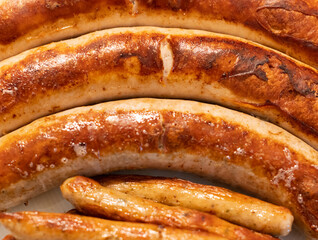 Feine Bratwurst gebraten in der Pfanne in einer Nahaufnahme