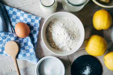 close up of egg, lemons and flour in bowl on table
