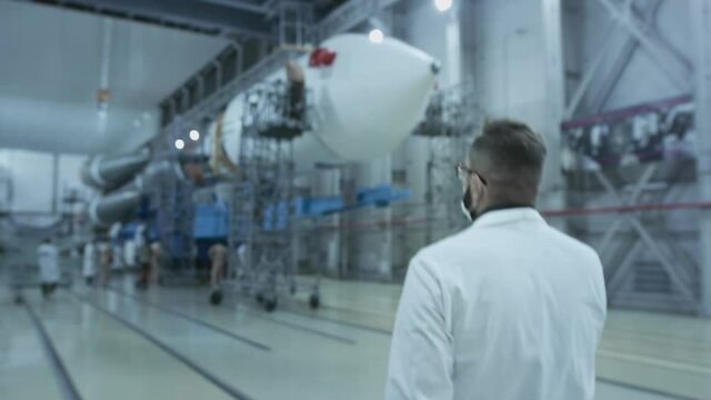 A scientist engineer inspects a spaceship, makes notes on a tablet. A space rocket in a military hangar being prepared for launch. Space technologies. Construction of Heavy Rocket. Humanity in Space