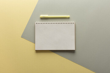 Open spiral notepad on gray and yellow background , notebook and pen lie on textural paper, flat lay concept in trendy colors of the year yellow and gray