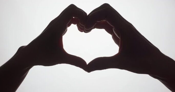 Silhouette of a heart from the hands of a man and a woman. Love concept. Valentine's Day.