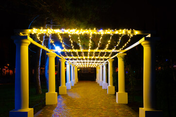 Illuminated gazebo with columns in the park in the evening.