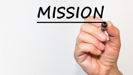 the hand writes text MISSION with a marker on a white background. business concept