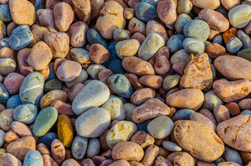 Sea pebbles of different colors on the beach near the sea.