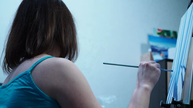 a girl draws a brush on a canvas standing on a tripod. home studio of fine arts.