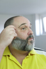 Obraz premium Man is brushing his beard with special metallic comb from beard grooming kit.
