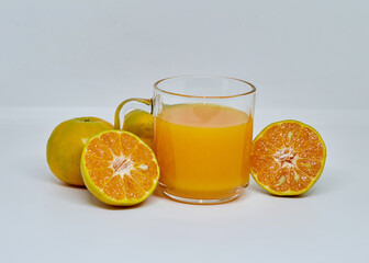 Orange juice in glass cup with sliced orange ripe on white background. Close up and selective focus, copy space.