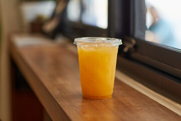 DISPOSABLE PLASTIC CUP DRINKS , plastic cup of tea for takeaway place on glass counter table in cafeteria. Close up and selective focus