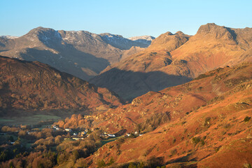 View of Langdale Pikes Mountains in golden morning light with clear blue Winter sky. Lake District, UK.