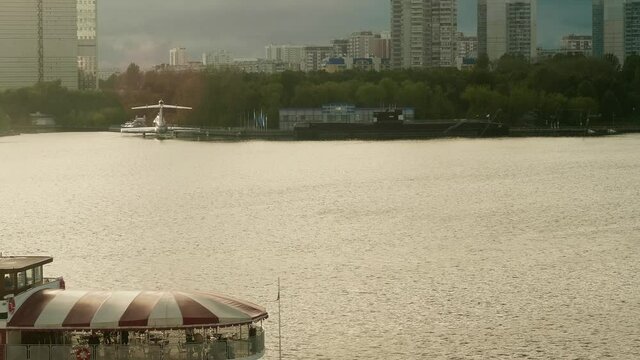 Faraway view of flare craft and model of black submarine on river Moskva in Moscow. Sunset in city