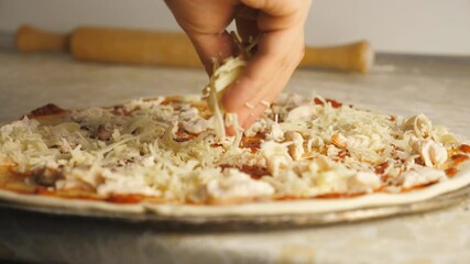 Male hands of cook putting grated cheese on pastry with ingredients in metal form at cuisine. Chef making italian pizza on a wooden surface at kitchen. Concept of cooking food. Close up Slow motion - Powered by Adobe