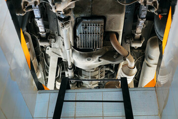 View of the car from the bottom of the repair pit. Diagnostics and repair of a vehicle in an auto...