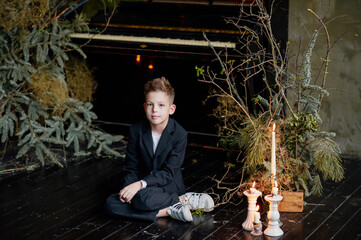 Cute boy with candlestick sitting on floor. .
