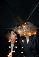 Son is kissing his beloved mother against the background of a garland.