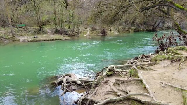 Riverbed with running waters and banks with trees in winter in a time lapse view. Ega river close to Estella city, Navarre, Spain. Europe.