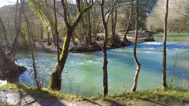 Riverbed with running waters and banks with trees in winter in a time lapse view. Ega river close to Estella city, Navarre, Spain. Europe.