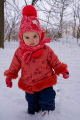 Toddler girl who walking by snow in the park. Frost winter season.