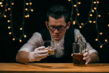 Barman pouring whiskey wearing protective mask on the bar counter