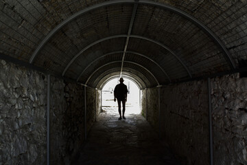 Silhouette of a man in a hat in a vaulted tunnel