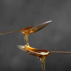 Spoons with raw honey bee on dark background, healthy nutrition concept