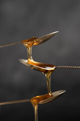 Spoons with raw honey bee on dark background, healthy nutrition concept