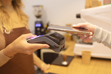 Close Up of a Woman Hand Holding a Smartphone with an NFC Payment Technology Used for Paying for Take Away Coffee in a Cafe.