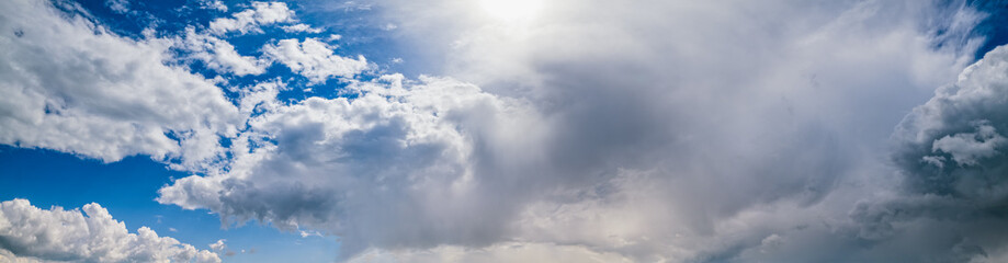 Blue sky with clouds in sunlight, wide cloudscape background panorama