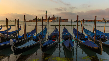 Fototapeta na wymiar Gondolas moored in St. Mark's Square facing San Giorgio Maggiore church. Dawn in Venice, Italy
