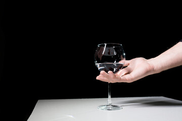 Wine glass and hand on a black background. 