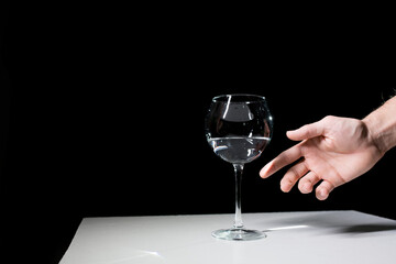 Wine glass and hand on a black background. 