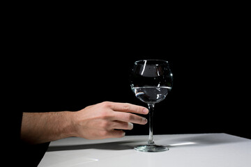 Wine glass and hand on a black background. 