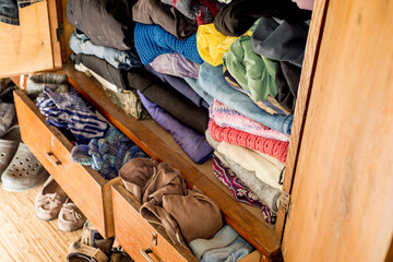 Old clothes and shoes in an overflowing closet. Second hand reuse. Decluttering and cleaning the...