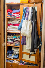 Wardrobe overflowing with clothes and things. Second hand reuse. Decluttering and cleaning the cabinet
