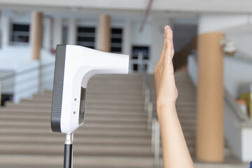 Young man used his palm to touch the sensor of the thermometer temperature using a non-contact infrared thermometer, Body temperature measurement device to prevent COVID-19 virus.