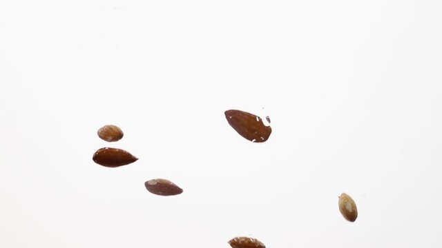 Almond nuts fall in water in an aquarium on white background, objects into liquid. healthy food concept