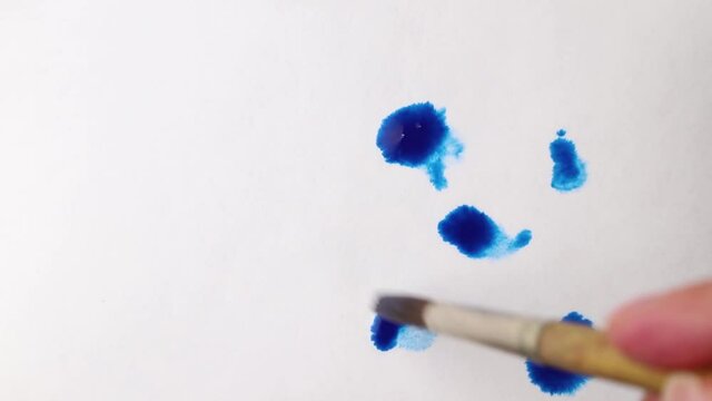 brush strokes of watercolor blue paint with stains on a sheet of white paper. psychedelic concept.