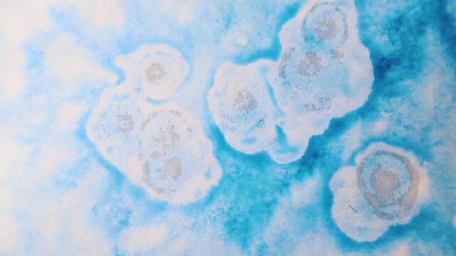 brush strokes of watercolor blue paint with stains on a sheet of white paper. psychedelic concept.