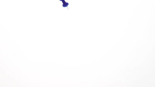 Colored pins fall in water in an aquarium on white background, objects into liquid. concept for school and office.