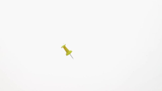 Colored pins fall in water in an aquarium on white background, objects into liquid. concept for school and office.