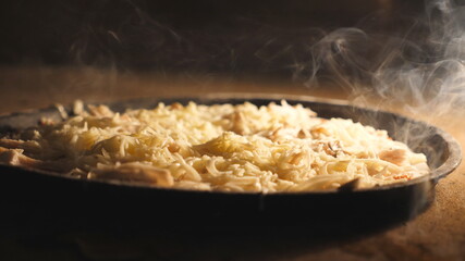 Delicious four cheese pizza is baking in electric oven at kitchen restaurant. Mozzarella, cheddar, parmesan and feta melting in furnace on the high temperature. Process of preparing food. Close up