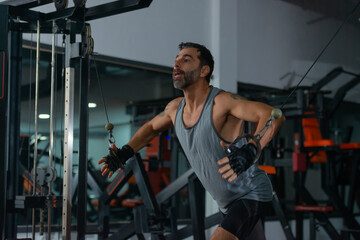 Fototapeta na wymiar A mature man exercising in the gym by pulling the sling for upper-back exercises
