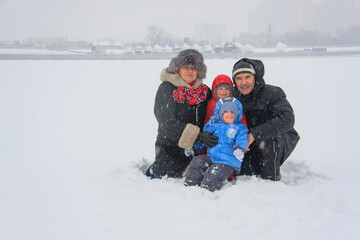 grandparents and their happy grandchildren sitting in the snow in  heavy snowfall