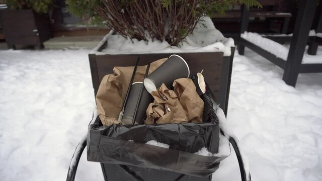Used coffee cup in the trash can female hand throws out trash, taking care of nature