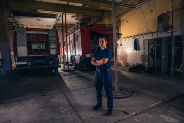 Fototapeta na wymiar Portrait of female firefighter standing against firetruck at station