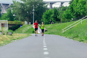 Young running couple jogging on an asphalt road in the park