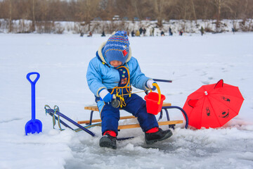 Fototapeta na wymiar little boy is fishing on a frozen lake in winter
