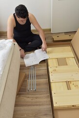 Man Assembling Cabinet Sitting Reading Installation Instruction At Home