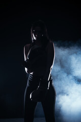 Fototapeta na wymiar Silhouette portrait with white smoke in the background of a female model with boxing gloves