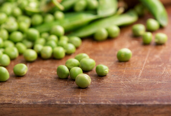 RAW baby peas in small white bowl, over retro wooden boards. Close-up.