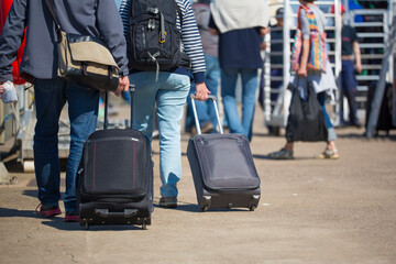 Back view close up of a traveler and suitcases in a travel location in a port on holidays.